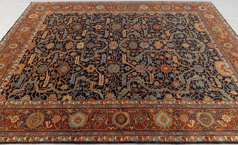 May include: A large, rectangular area rug with an intricate floral pattern. The rug features a dark navy blue background with a detailed design in shades of rust, gold, and teal. A wide border in rust color frames the central design.