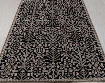 May include: Black and beige area rug with a geometric pattern featuring stylized trees and floral motifs.