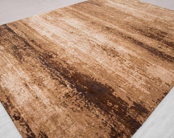 May include: A rectangular area rug with a textured, abstract design. The rug features a blend of brown, beige, and cream tones, with darker brown streaks creating a visual pattern. The rug's design gives a sense of depth and warmth.
