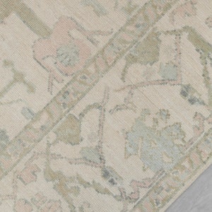 May include: A close-up of a beige rug with a faded floral pattern in shades of pink, blue, and green.
