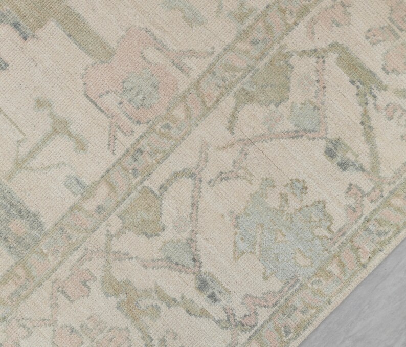 May include: A close-up of a beige rug with a faded floral pattern in shades of pink, blue, and green.