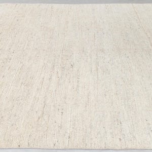 May include: A natural fiber rug with a light beige color and a woven texture. The rug has a subtle sheen and a slightly rough surface.