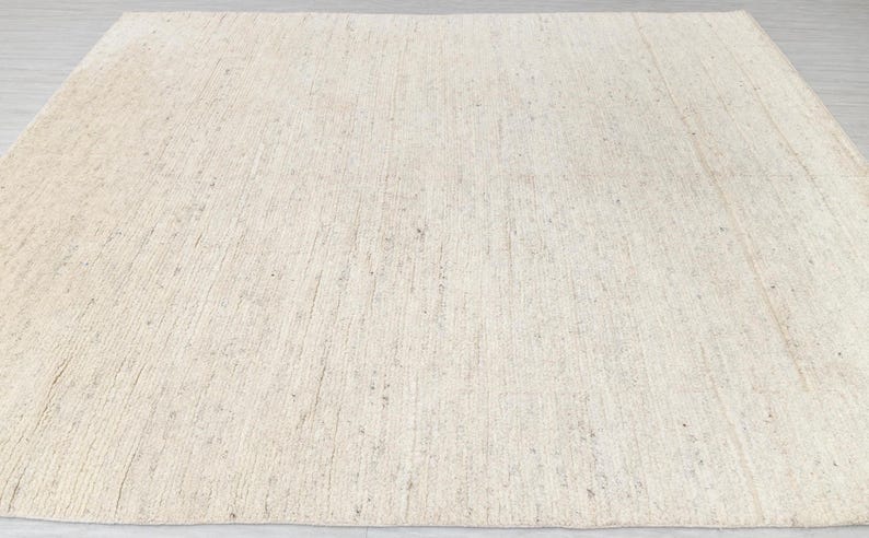 May include: A natural fiber rug with a light beige color and a woven texture. The rug has a subtle sheen and a slightly rough surface.