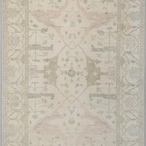 May include: A beige rug with a light pink and green floral pattern. The rug has a central medallion with a diamond shape and a border with a repeating floral design.