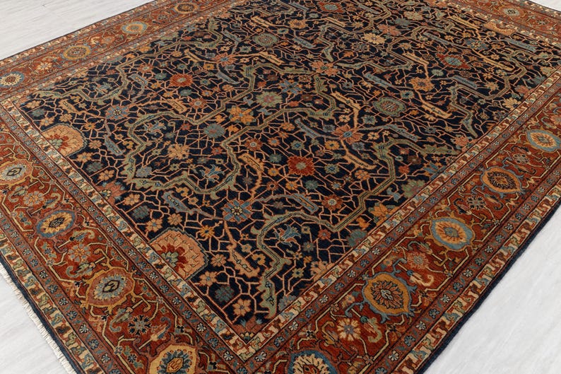 May include: An ornate, rectangular rug with a dark navy blue field and a detailed floral pattern in shades of orange, teal, and beige. The border is a rich reddish-brown with repeating floral medallions. The rug's design is intricate and traditional.