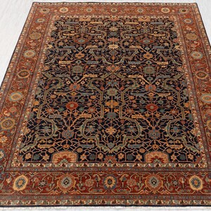 May include: A large, rectangular area rug with an intricate, traditional design. The rug features a dark navy blue central field with a complex pattern of floral and geometric motifs in shades of rust, green, and gold. A wide border in rust-red frames the design.