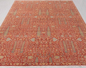 May include: A large, rectangular rug with an intricate floral pattern in shades of red, beige, and blue. The rug features a detailed design of stylized trees and flowers, with a fringed border along the bottom edge.