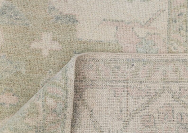 May include: A close-up of a light beige rug with a subtle pattern. The rug has a woven texture and a fringed edge.