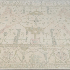 May include: A cream-colored rug with a traditional Persian design. The rug features a central medallion with intricate floral patterns in shades of pink, green, and beige.