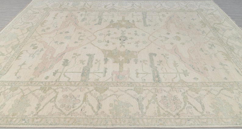 May include: A cream-colored rug with a traditional Persian design. The rug features a central medallion with intricate floral patterns in shades of pink, green, and beige.