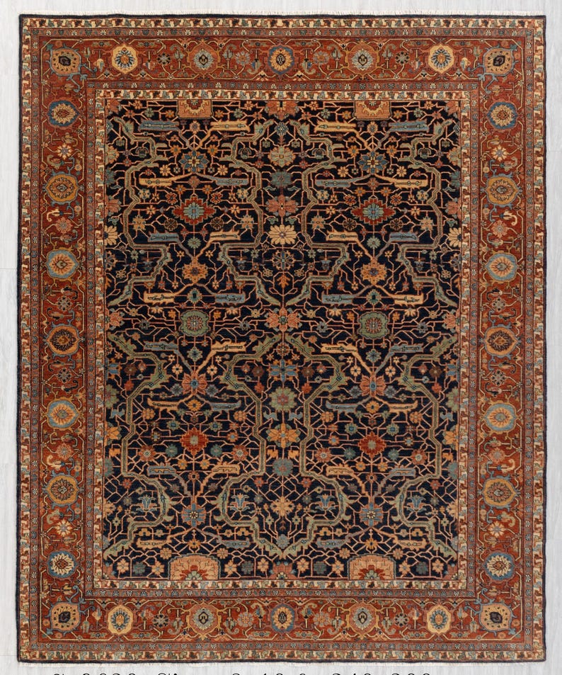 May include: A large, rectangular rug with an intricate, floral pattern. The rug features a dark navy blue field with a complex design in shades of rust, teal, and gold. A wide border in rust-red frames the central design, adding a contrasting element.
