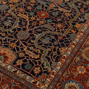 May include: An ornate, rectangular rug with a dark blue background and a complex floral pattern in shades of red, orange, and blue. The rug has a detailed border and intricate design.