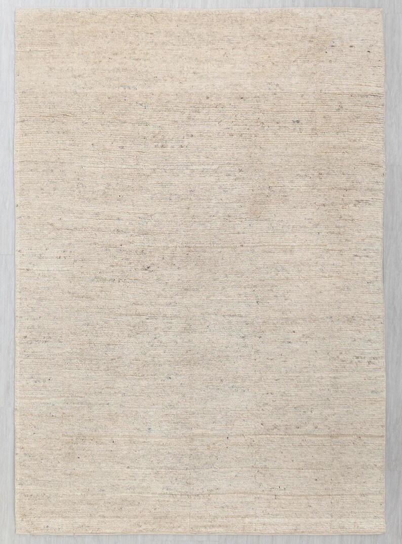 May include: A plain, off-white woven rug with a subtle texture. The rug is made of natural fibers and has a slightly rough surface.
