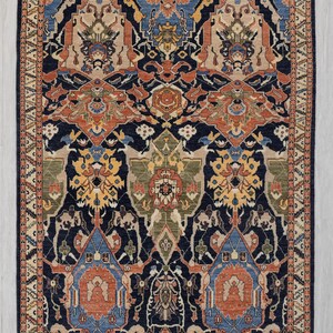 May include: A rectangular rug with a detailed, symmetrical pattern. The rug has a navy blue base with designs in orange, beige, blue, and green. The border is a lighter beige with a repeating geometric design. The rug is suitable for a living room.