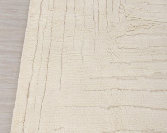 May include: A cream-colored rug with a textured, woven design and fringe along the bottom edge.
