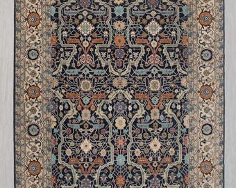 May include: A traditional Persian rug with a navy blue background and intricate floral patterns in shades of beige, orange, and blue. The rug has a cream-coloured border with a repeating floral design.