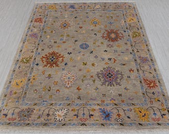 May include: A gray rug with a floral pattern in shades of blue, red, yellow, and green. The rug has a border with a repeating design.