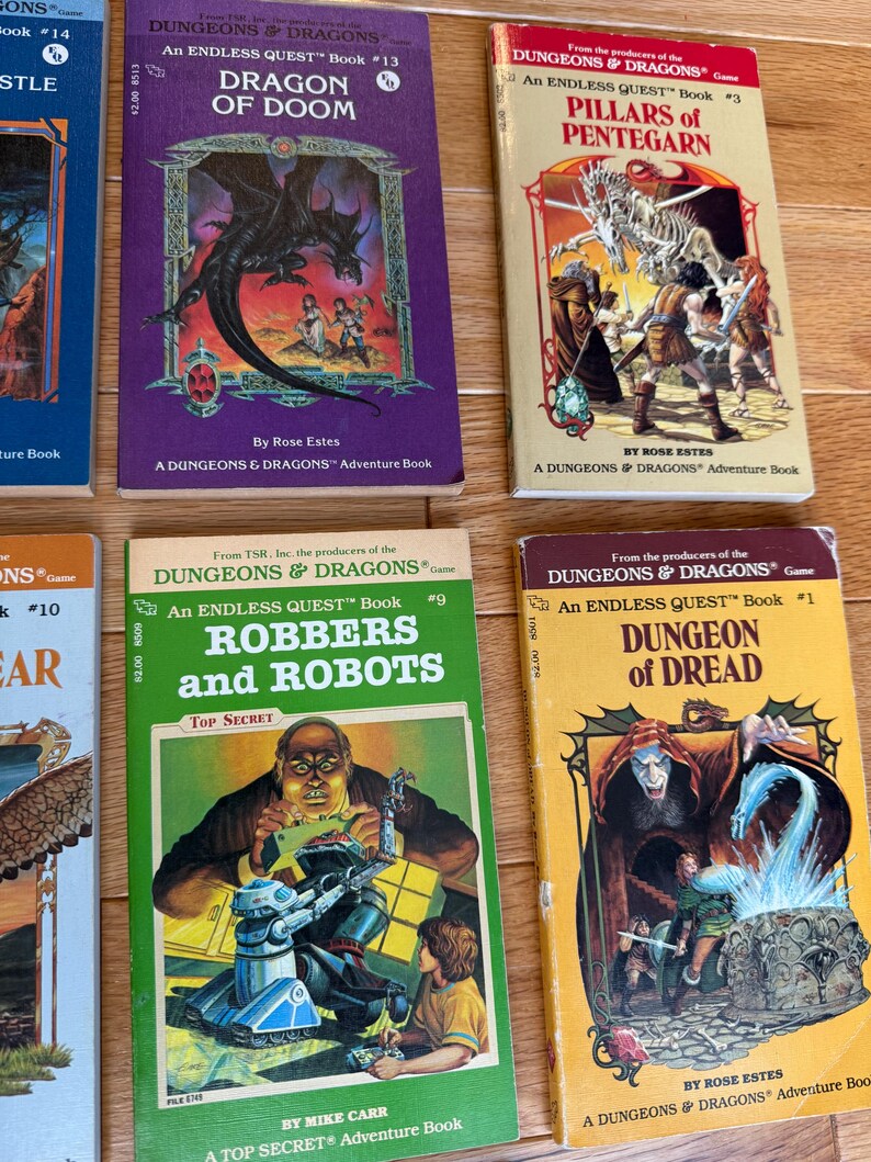 May include: A collection of vintage "Dungeons & Dragons" adventure books. The covers feature fantasy illustrations of dragons, robots, and dungeons. Titles include "Dragon of Doom," "Pillars of Pentegarn," "Robbers and Robots," and "Dungeon of Dread."