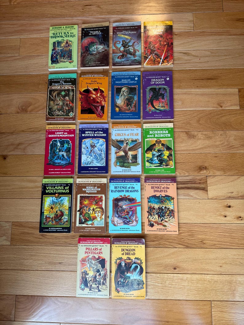 May include: A collection of vintage "Dungeons & Dragons" adventure books, featuring colorful covers with fantasy illustrations. Titles include "Return to Brookmere," "Dragon's Wing," and "Revolt of the Dwarves." The books are arranged on a wooden surface.