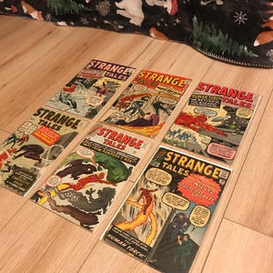 May include: A collection of six vintage comic books featuring the Human Torch. The comic books are all titled "Strange Tales" and feature various covers with the Human Torch in action. The comic books are in good condition and have a vintage look.
