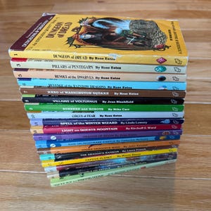 May include: A stack of vintage fantasy adventure books, featuring titles like "Dungeon of Dread" and "Revolt of the Dwarves." The books have colorful spines and illustrations, with titles and authors clearly visible. The books are stacked on a wooden surface.