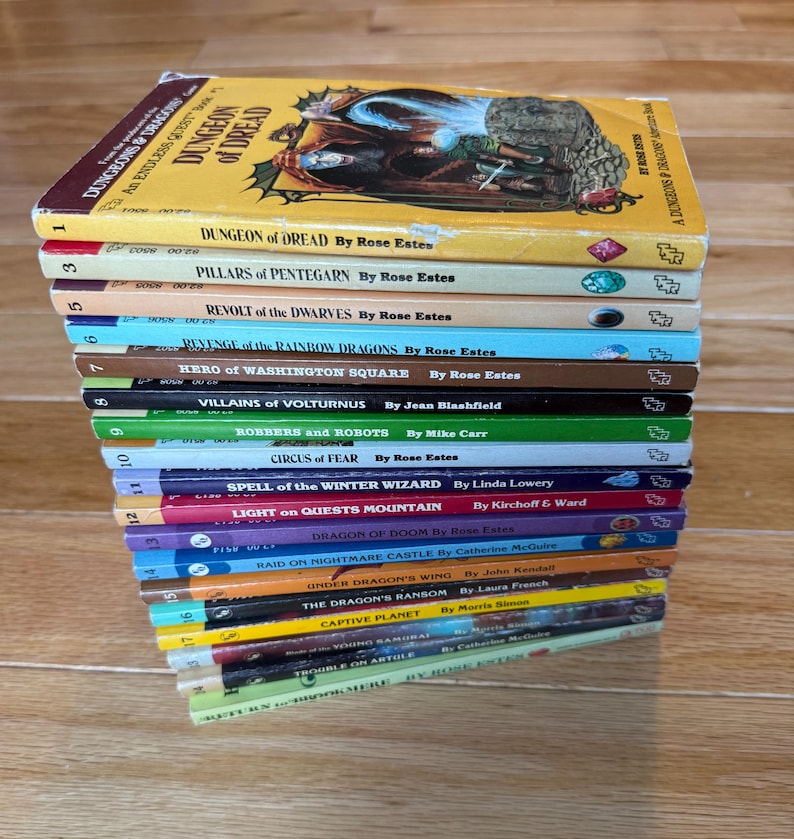 May include: A stack of vintage fantasy adventure books, featuring titles like "Dungeon of Dread" and "Revolt of the Dwarves." The books have colorful spines and illustrations, with titles and authors clearly visible. The books are stacked on a wooden surface.