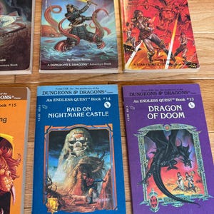 May include: A collection of vintage "Dungeons & Dragons" adventure books. The covers feature fantasy illustrations of samurai, dragons, and other creatures. Titles include "Blade of the Young Samurai," "Captive Planet," "Raid on Nightmare Castle," and "Dragon of Doom."