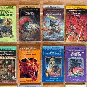 May include: A collection of vintage "Dungeons & Dragons" Endless Quest books. The covers feature fantasy illustrations of dragons, warriors, and other creatures. Titles include "Return to Brookmere," "Trouble on Artule," and "Dragon of Doom."