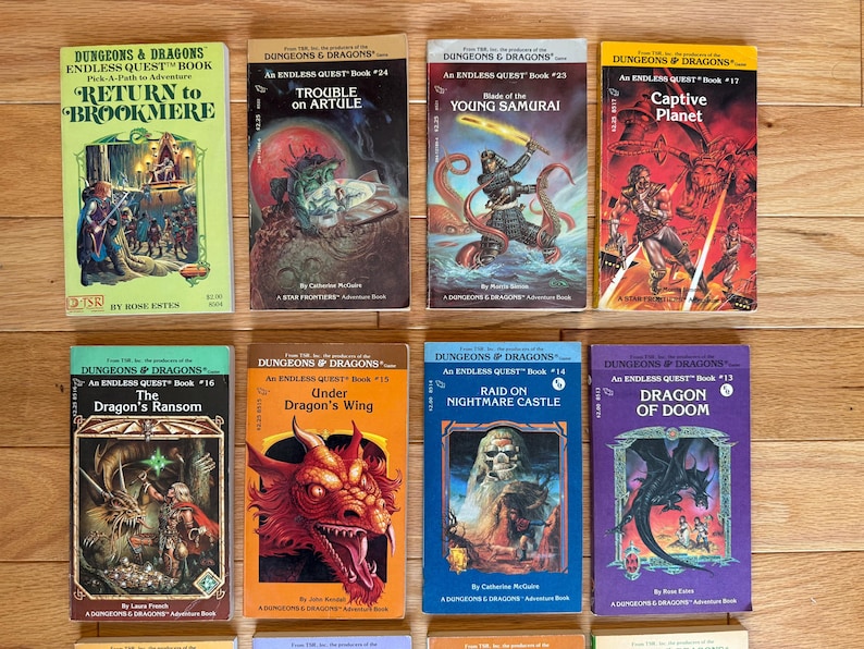 May include: A collection of vintage "Dungeons & Dragons" Endless Quest books. The covers feature fantasy illustrations of dragons, warriors, and other creatures. Titles include "Return to Brookmere," "Trouble on Artule," and "Dragon of Doom."