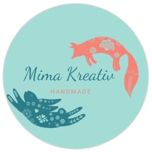 Op de afbeelding: Een turquoise cirkel met een roze vos en een blauwe konijn met bloemenpatronen. De tekst "Mima Kreativ Handmade" staat in het midden.