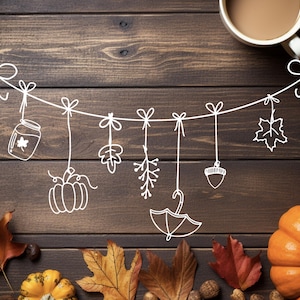 Op de afbeelding: Een witte string met herfstdecoraties hangt aan een bruine houten achtergrond. De decoraties omvatten een pot, een pompoen, een blad, een bloem, een eikel en een paraplu. Er zijn ook herfstbladeren en een pompoen onderaan de afbeelding.
