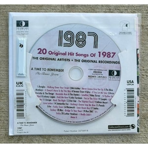 以下が含まれることがあります： 1987年の音楽コンピレーションCD「20 Original Hit Songs of 1987」。様々なアーティストによる20曲のトラックリストが記載されています。ディスクは、バーコード、CDCard Companyのロゴ、Sony BMGのブランド名が印刷された白い段ボール製のメールケースに収められています。