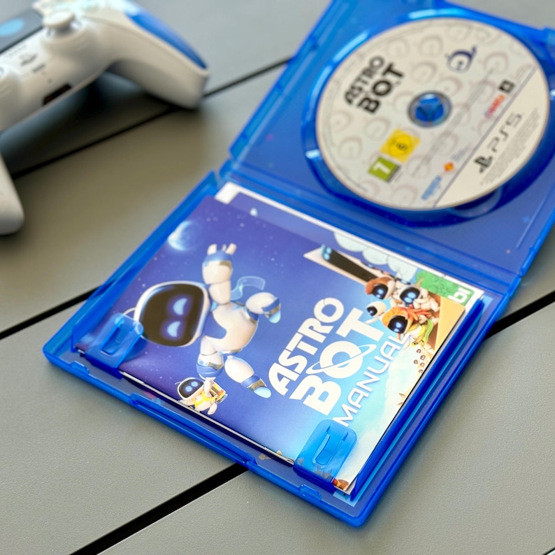 May include: A blue PlayStation 4 game case with a white disc inside. The case is open and the manual for the game Astro Bot: Rescue Mission is visible. The manual has a cartoon robot on the cover.