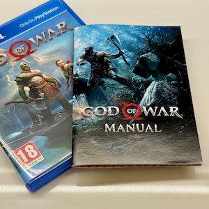 May include: A PlayStation 4 game case and manual for "God of War." The game case is blue with the game title and character art. The manual features the game's title and a warrior illustration.