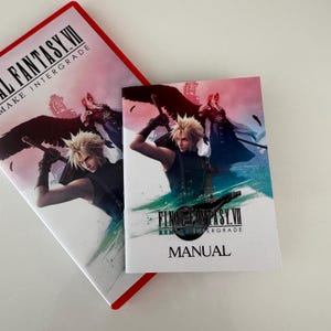 May include: Two Final Fantasy VII Remake Intergrade manuals. The covers feature a character with spiky blonde hair wielding a sword, set against a pink and blue background. The word "MANUAL" is printed on the smaller book.