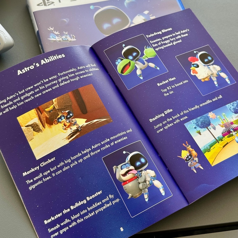 May include: A colorful illustrated guide to Astro's abilities in the video game Astro's Playroom. The guide features illustrations of Astro using different abilities, such as the Twin-Frog Gloves, Rocket Hen, Dashing Dillo, Monkey Climber, and Barkster the Bulldog Booster. The guide also includes text describing each ability.