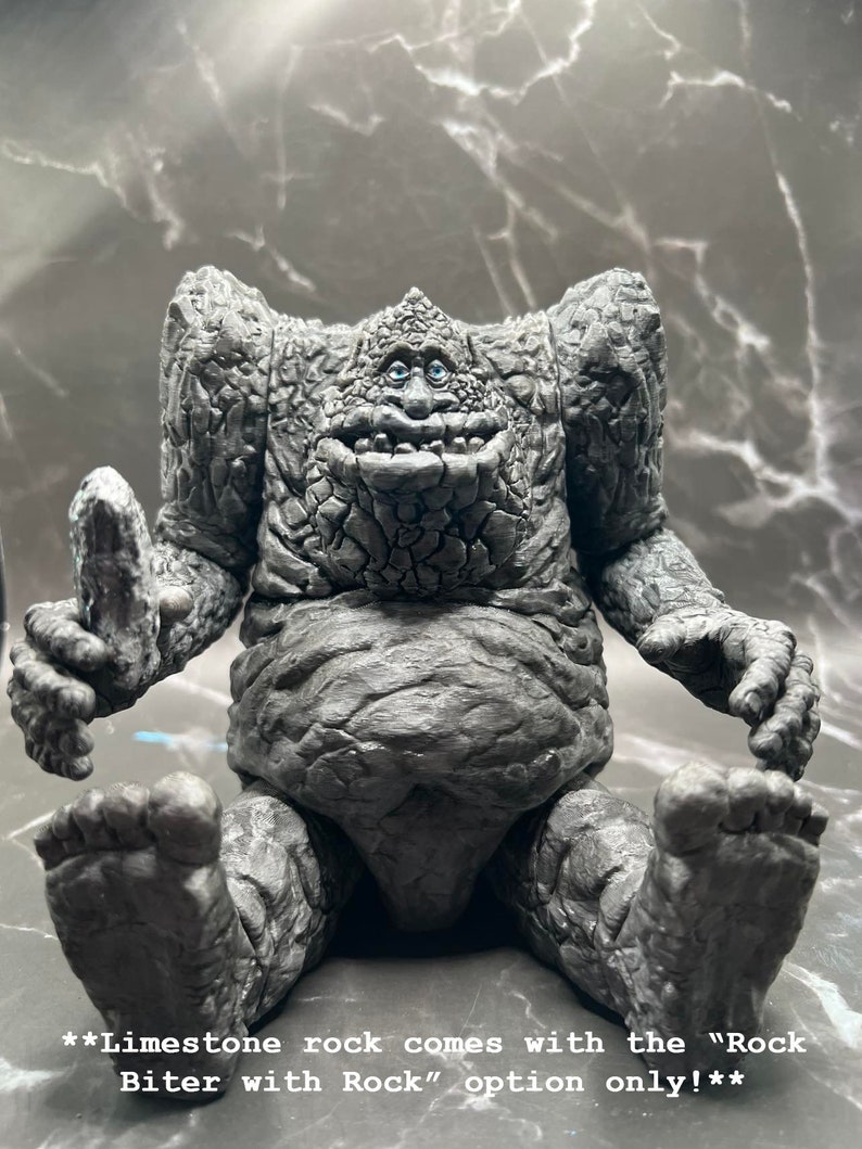 May include: A grey, stone-like figure with a wide smile and blue eyes. The figure is sitting with its legs crossed and has a rough, textured surface. **Limestone rock comes with the "Rock Biter with Rock" option only!**