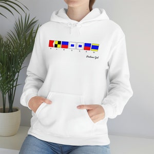 Puede incluir: Sudadera con capucha blanca con bolsillo delantero. El diseño presenta la palabra "BLESSED" en banderas de señales náuticas, con "Pontoon Girl" impresa debajo. La sudadera está hecha de un material suave.