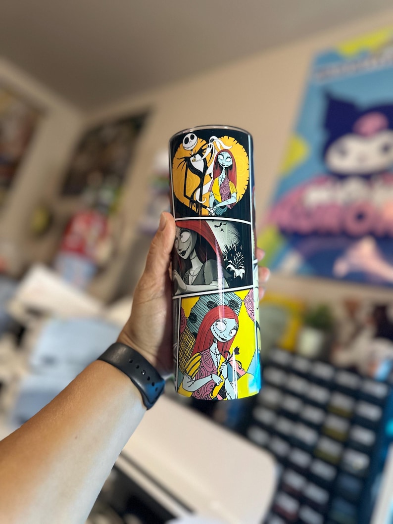 May include: A black and white stainless steel tumbler with a colorful comic book style design featuring characters from the Nightmare Before Christmas. The tumbler features Jack Skellington and Sally.