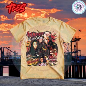 Może przedstawiać: Jasnobrązowy t-shirt z grafiką z filmu "The Lost Boys". Projekt zawiera tekst "Vampires Everywhere!" i "Santa Carla". Koszulka ma okrągły dekolt i kr&oacute;tkie rękawy.