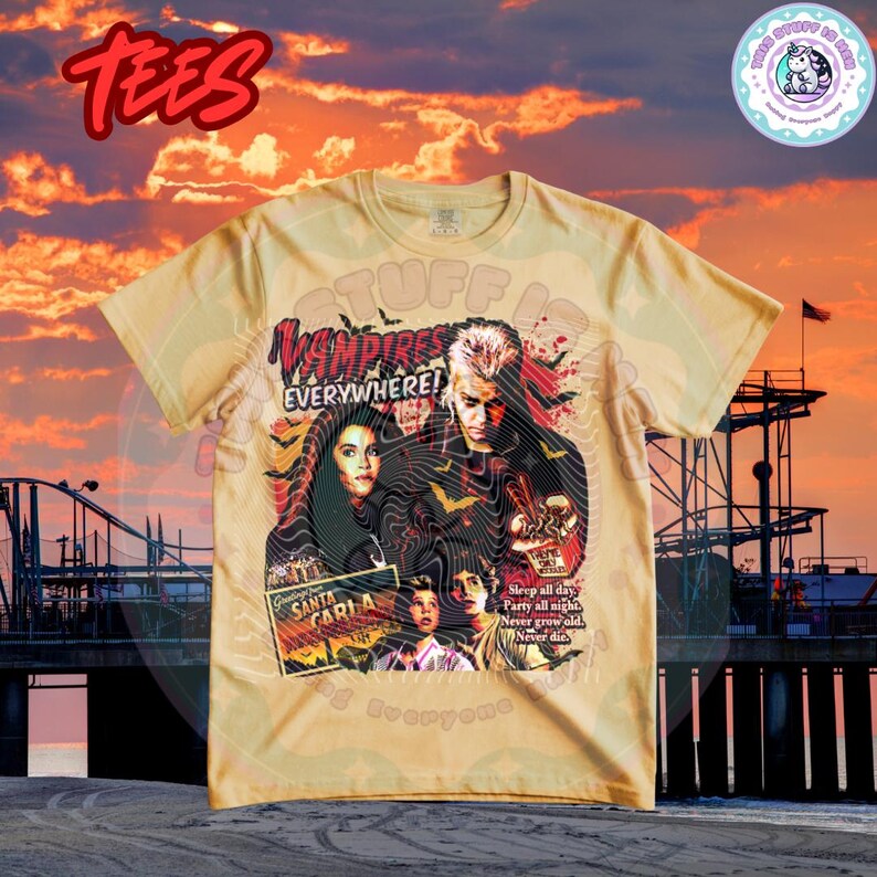 Może przedstawiać: Jasnobrązowy t-shirt z grafiką z filmu "The Lost Boys". Projekt zawiera tekst "Vampires Everywhere!" i "Santa Carla". Koszulka ma okrągły dekolt i kr&oacute;tkie rękawy.