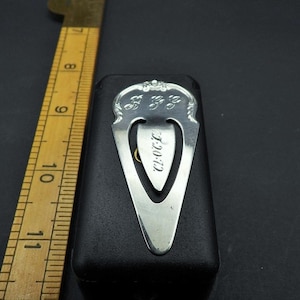 May include: Silver bookmark with a decorative design and the word "CLOVER" engraved on it. The bookmark is in a black velvet box.