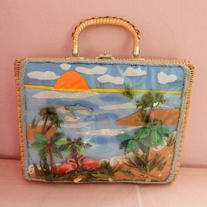 May include: A wicker handbag featuring a scene of a beach sunset, palm trees, dolphins, and flamingos. The scene is crafted from felt and other materials and is set against a blue background.