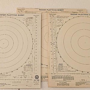 May include: Three beige paper radar plotting sheets with black printed markings. Two sheets are labeled Radar Plotting Sheet and one is labeled Radar Transfer Plotting Sheet. Each features concentric circles, degree scales, and technical data tables.