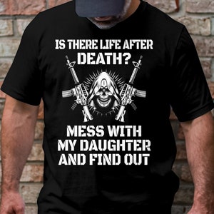 May include: Black t-shirt with a white graphic design. The graphic features a skull with a hooded cloak, two rifles crossed behind the skull, and the text "Is there life after death? Mess with my daughter and find out."