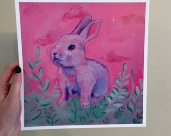 May include: A pink rabbit sits in a field of green foliage against a pink sky with white clouds. The rabbit has a pink nose and white whiskers.