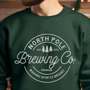 May include: A dark green sweatshirt with a white circle logo that says "North Pole Brewing Co. Est. 1773 Premium Making Spirits Bright".