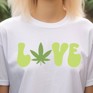 May include: White t-shirt with a green marijuana leaf and the word "LOVE" in green letters.