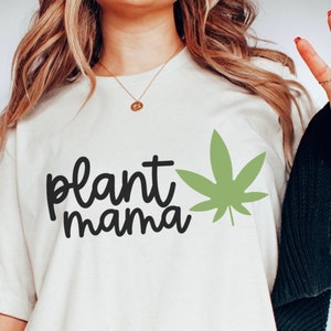 May include: White t-shirt with black text that says "plant mama" and a green marijuana leaf graphic.