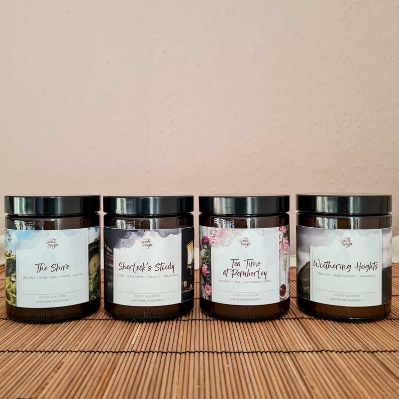 May include: Four brown glass candle jars with black lids and labels. The labels feature illustrations and text. The candles are labeled "The Shire", "Sherlock's Study", "Tea Time at Pemberley", and "Wuthering Heights".
